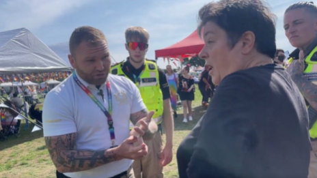 A still taken from a video showing three security staff in a discussion with a woman. They are a festival-style event in a field