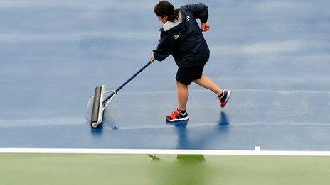 A member of the Flushing Meadows ground staff dries the court