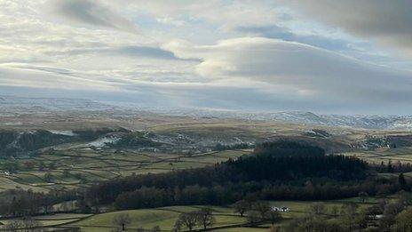 Clouds and glimmers of blue sky over rolling hills in Newbiggin, County Durham.