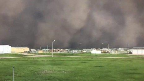 A dust storm fills the air as it sweeps over a green playing field in South Dakota, US.