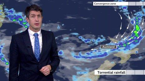 Chris Fawkes standing in front of a weather map of New Zealand