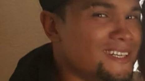 A man smiling into the camera. Only part is his face is visible as the image is cut off at the chin and eyebrows. He has brown eyes and a short, black beard.
