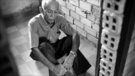 Chum Mey poses for photo at his former cell in the Tuol Sleng prison (July 2010)