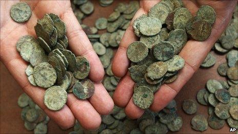 A British Museum staff member displays handfuls of the coins