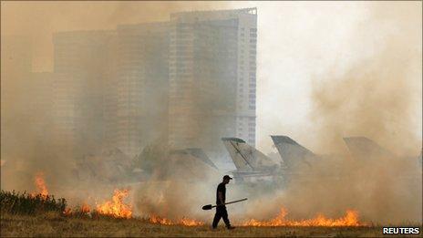 A security guard walks near a fire caused by the heatwave at an aviation museum in Moscow, 29 July 2010