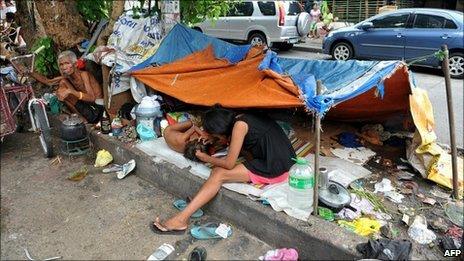 A homeless living under a tarpaulin on a flower bed in the middle of Manila on 2 September, 2010