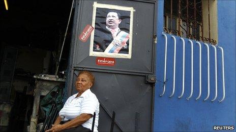 A woman sits outside a shop with a picture of Venezuelan President Hugo Chavez on the door in Caracas on 17 September 2010