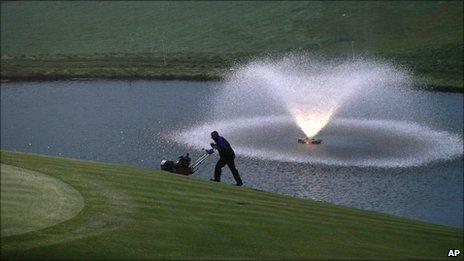 A greenkeeper prepares the 18th green for the 2010 Ryder Cup golf tournament in Newport