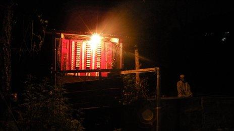 A man prays in darkness as light shines on him from inside a hydropower generator