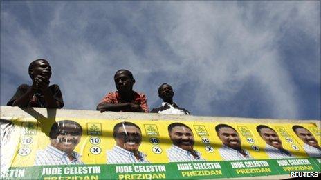 Haitians look at supporters of presidential candidate Jude Celestine march in a rally in Port-au-Prince on 21 November, 2010.