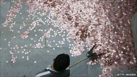 A worker gathers coins thrown by tourists into a well to pray for good luck and wealth at a temple in Beijing