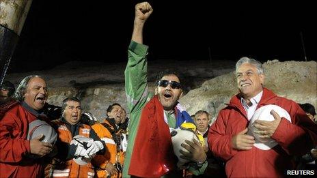 The last miner to be rescued, Luis Urzua, who is credited with organizing the miners to ration food and save themselves, gestures next to Chilean President Sebastian Pinera on 13 October