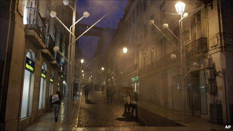 People walk under rain in central Lisbon, Portugal