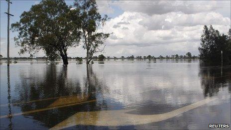 Water flows over road markings on a highway near Rockhampton on 3 Jan 2010