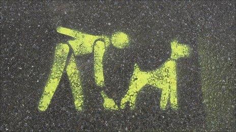 Stencil on pavement of dog owner cleaning up dog mess