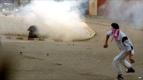 Youth face police forces in Algiers, Algeria Sunday Jan. 9, 2011, during the funeral ceremony of Abdelfattah Akriche, a 32 year old demonstrator who was killed during riots in Bousmail, south of Algiers