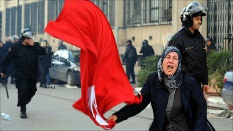 A Tunisian woman waves the national flag in front of the interior ministry during clashes between demonstrators and security forces in Tunis on January 14, 2011