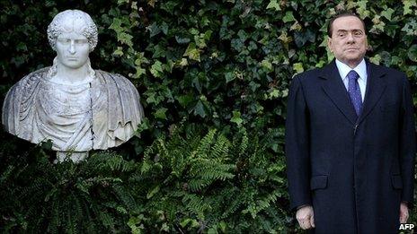 Silvio Berlusconi poses beside a bust at Rome's Villa Madama, 18 January
