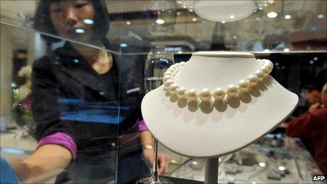 A worker checks a pearl necklace on display in Beijing.