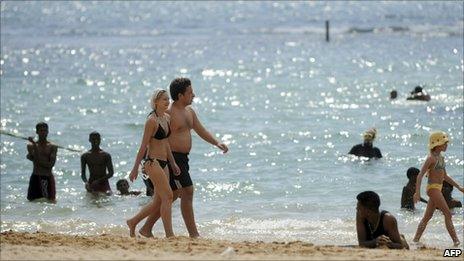 Tourists walk on a beach in Sri Lanka's southern coastal city of Hikkaduwa, 30 January 2011