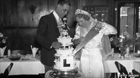 Newlyweds cutting cake with L plate on