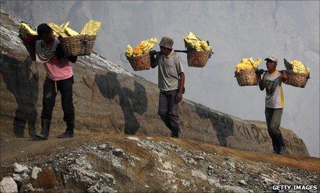 Heavily-laden miners walk back up out of the crater