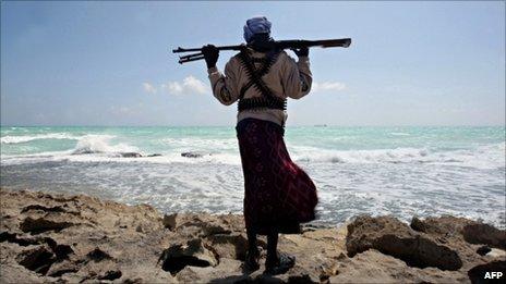 Armed man on coast of Somalia with MV Filitsa, seized by pirates, in distance - 26 January 2010