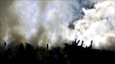 A worker walks past the burning embers of pigs and cattle carcasses at Burnside Farm, Northumberland