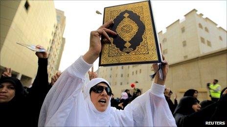 An anti-government protester holds a copy of the Koran as she passes by the Saudi Embassy in Manama, 15 March 2011