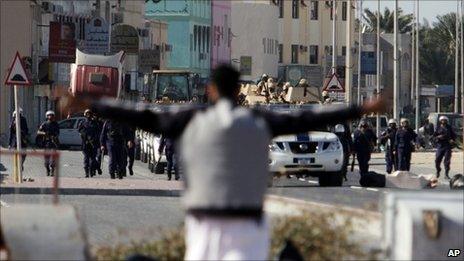 A resident spreads his arms in front of riot police in Malkiya, 20 March