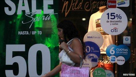 A woman walks past a shop with signs offering discounts in Buenos Aires. Photo: March 2011