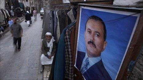 A shopkeeper in Sana'a waits for customers next to a poster of President Saleh. Photo: March 2011