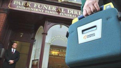 A man holding a defibrillator outside funeral home