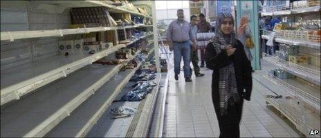 Libyans walk in between near empty shelves at a supermarket in Tripoli, Libya, Tuesday 3 May 2011
