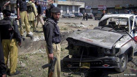 Policemen and paramilitary forces stand at the scene of a suicide bomb blast in Dir, northwest Pakistan April 4, 2011