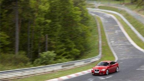 BBC reporter Jorn Madslien driving a salsa red Jaguar KFR at the Nurburgring