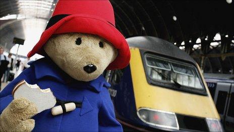 Paddington Bear with marmalade sandwich in hand, about to board a train at Paddington station