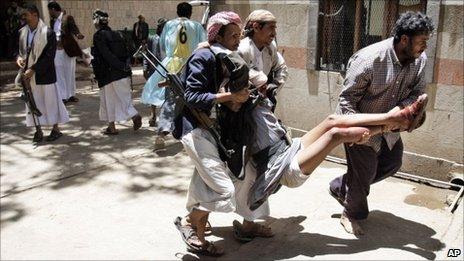 Tribesmen carry an injured colleague during clashes with Yemeni security forces in Sanaa, Yemen, on 24/5/11