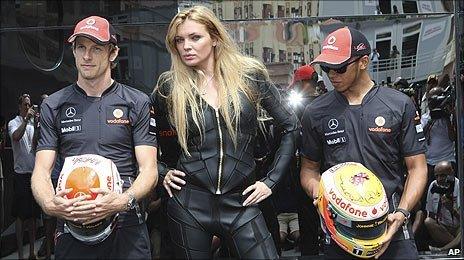 Jenson Button and Lewis Hamilton pose with their new helmets and a model in Monaco