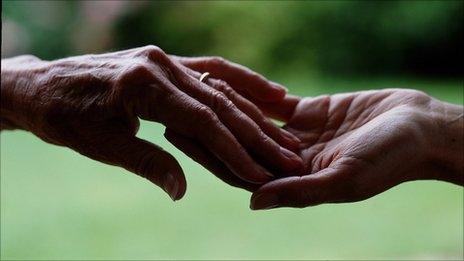 Elderly hand touching a younger hand