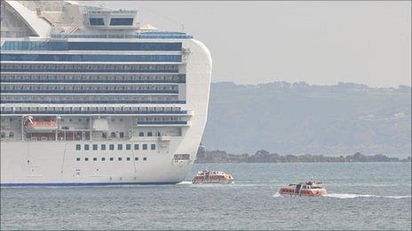 Cruise ship liberty boats travel to and from the Crown Princess anchored off Guernsey