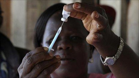 Health worker in West Africa takes a dose of a vaccine