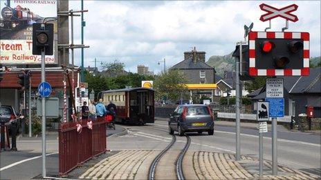 Car following a train across a level crossing at Porthmadog