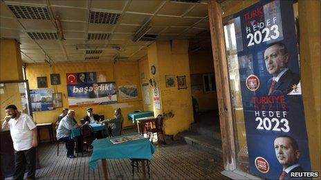 Men sit in a tea house in Istanbul with Prime Minister Tayyip Erdogan's election campaign posters on the window, 9 June