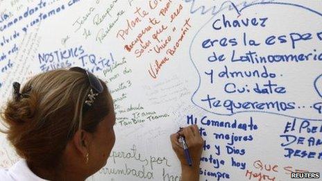 A woman writes a message to Venezuelan President Hugo Chavez on a wall during an event to support him in Caracas June 12, 2011.