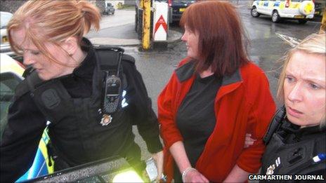 Jacqui Thompson is led away in handcuffs from the council meeting