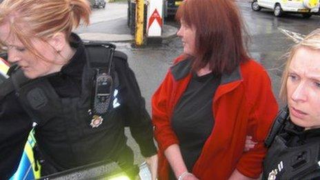 Jacqui Thompson is led away in handcuffs from the council meeting