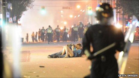 Couple between police and rioters in Vancouver, Canada (16 June 2011)