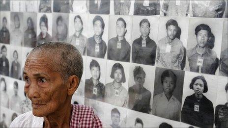 A survivor of the Khmer Rouge regime stands in front of portraits of victims at the Tuol Sleng (S-21) genocide museum in Phnom Penh