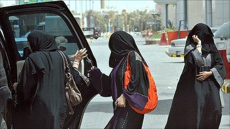 Saudi women get in the back seat of a car